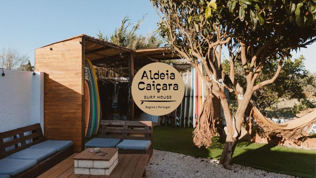 a sign for a caffe calaza with a bench and a tree at Aldeia Caiçara Surf House in Sagres