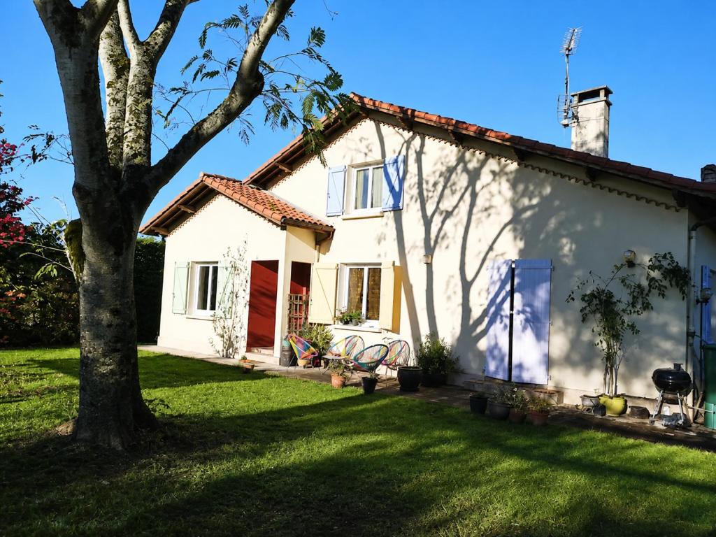 a white house with a tree in the yard at Santon in Eugénie-les-Bains
