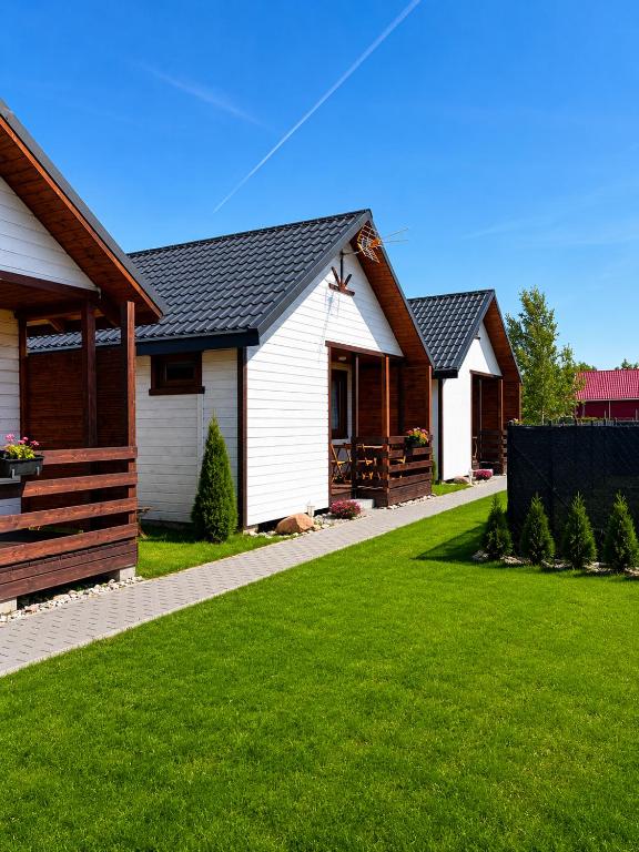 a row of houses in a yard with green grass at Domki letniskowe MagNat 700m od morza! in Rusinowo
