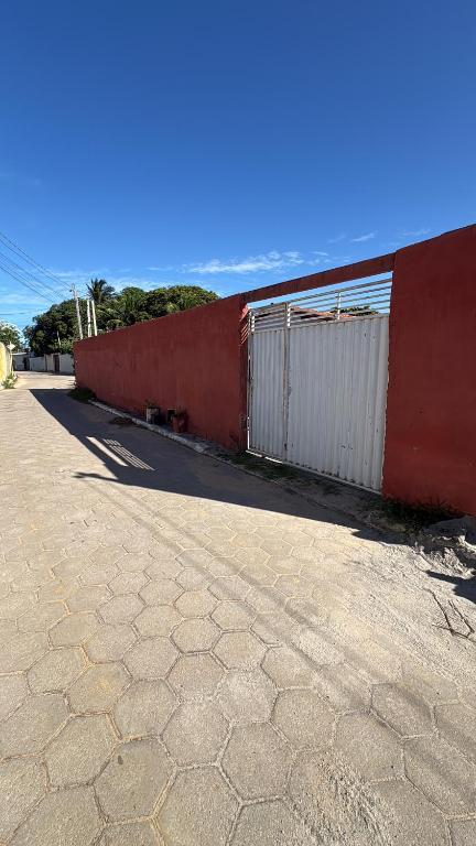 a red wall next to a brick road at Praia de Pitangui in Extremóz