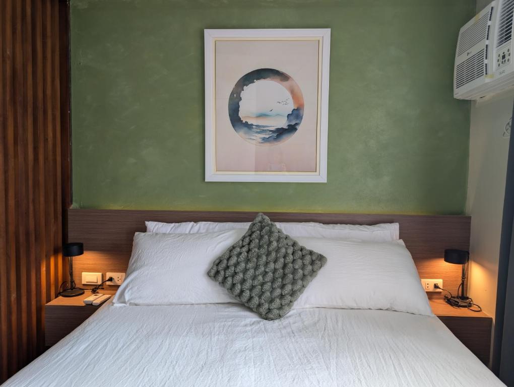a bedroom with a white bed with two lamps and a picture at Relaxing Pool-View Studio in Mactan with Balcony in Lapu Lapu City
