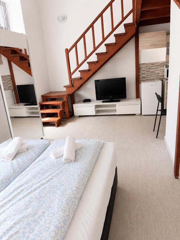 two beds in a room with a tv and stairs at Holdfény apartman in Siófok