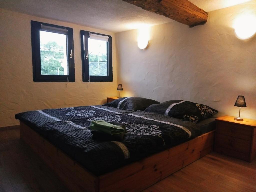 a bed in a room with two windows at Ferienhaus an der Felsenkirche in Idar-Oberstein