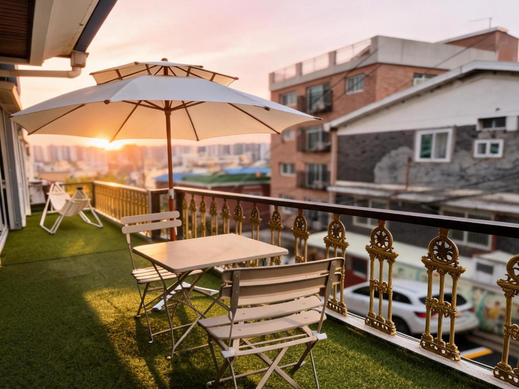 a table and chairs on a balcony with an umbrella at 곁 Stay in Seoul