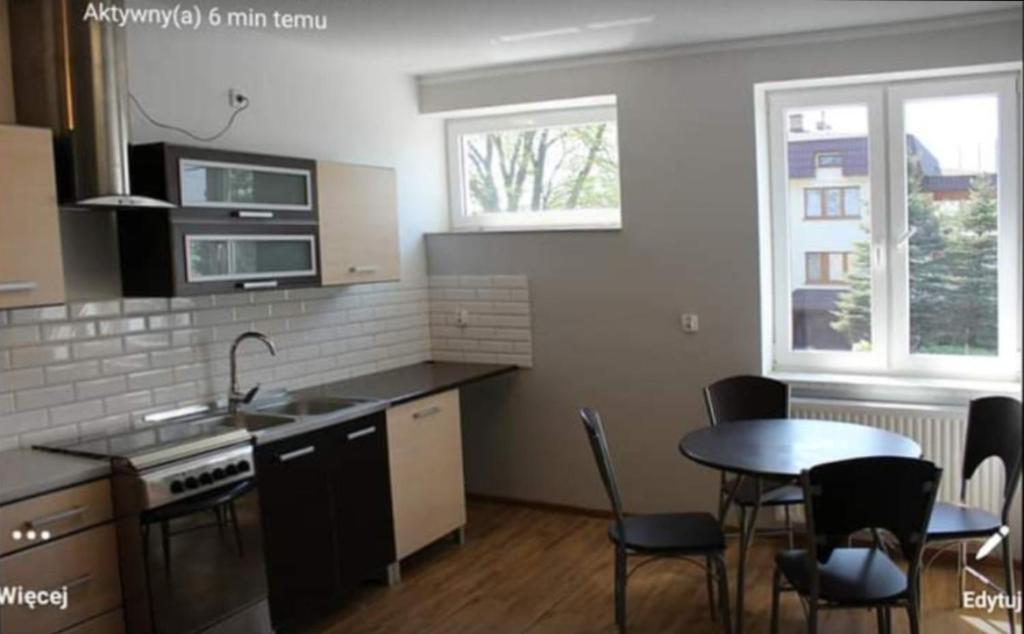 a kitchen with a table and chairs and a kitchen with a sink at Hostel Lubawa in Lubawa