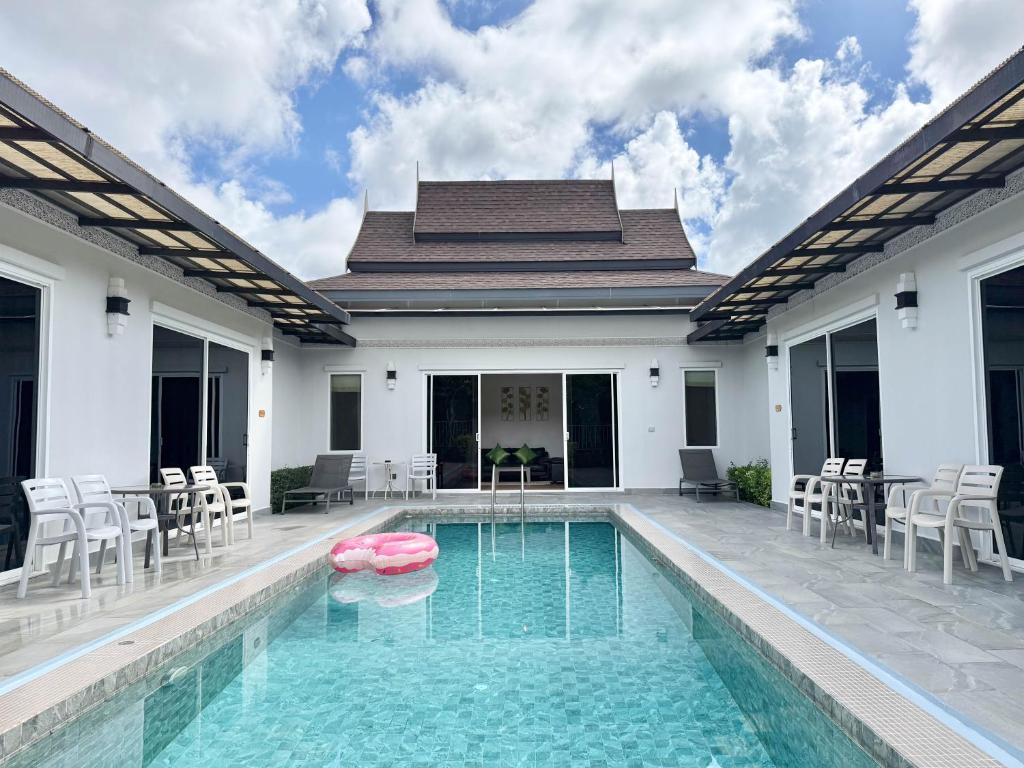 a swimming pool with chairs and a house at Phuket La Siesta, Naiharn Beach in Nai Harn Beach