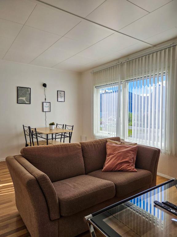 ein Wohnzimmer mit einem braunen Sofa und einem Tisch in der Unterkunft Bergsbu in Senja