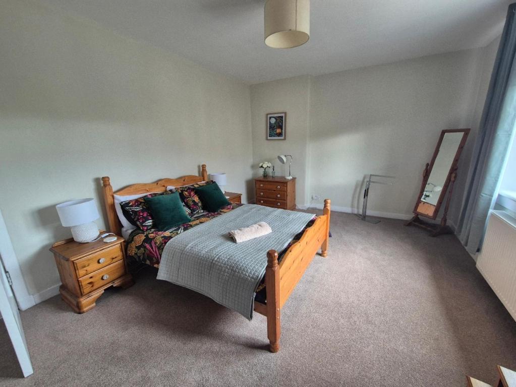 a bedroom with a bed with green pillows and a table at Spacious 2 Bedroom Flat in Coatbridge in Coatbridge