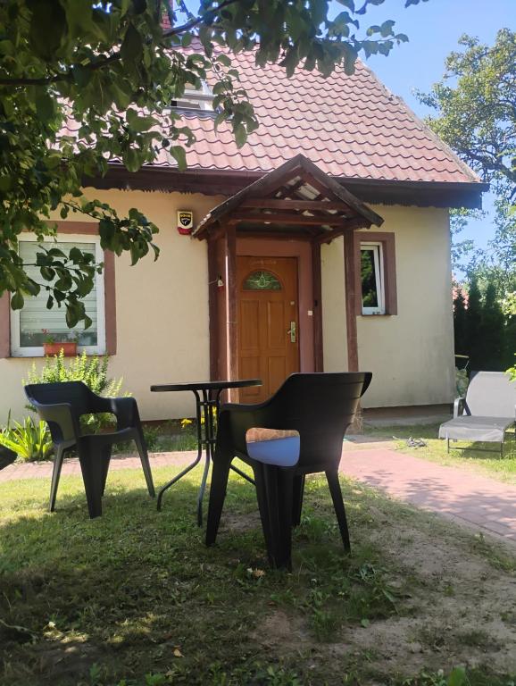 three chairs and a table in front of a house at Lipowy domek Mazury in Piecki