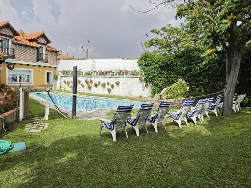 a row of chairs sitting next to a swimming pool at Hospedium Hacienda Las Cavas in Olmedo