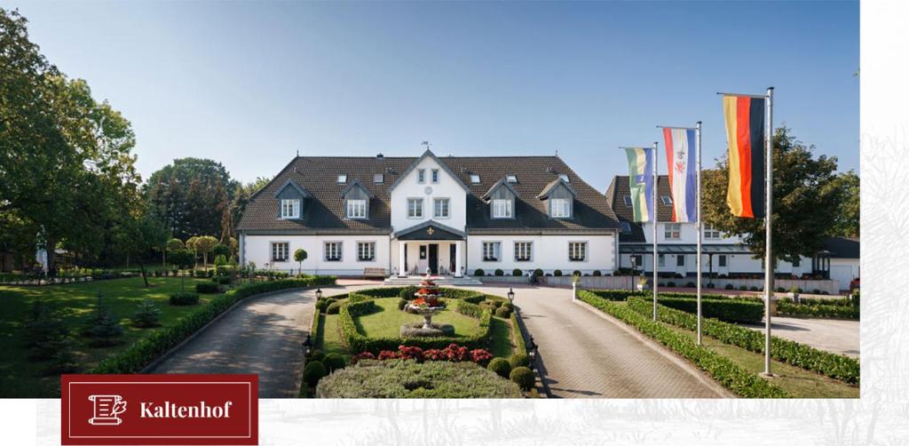 a large white house with a garden in front of it at Pension und Restaurant Gutshaus Kaltenhof in Kaltenhof