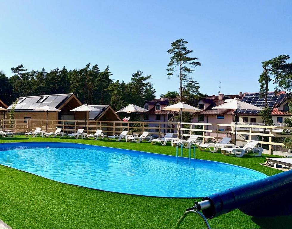 a large swimming pool with lawn chairs and buildings at Bursztynowo Kąty Rybackie in Kąty Rybackie