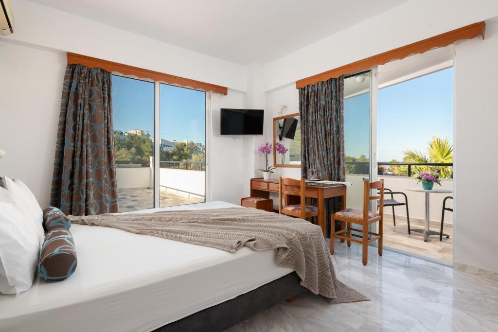 a bedroom with a bed and a desk and a balcony at Vlycha Beach Apartments in Lindos