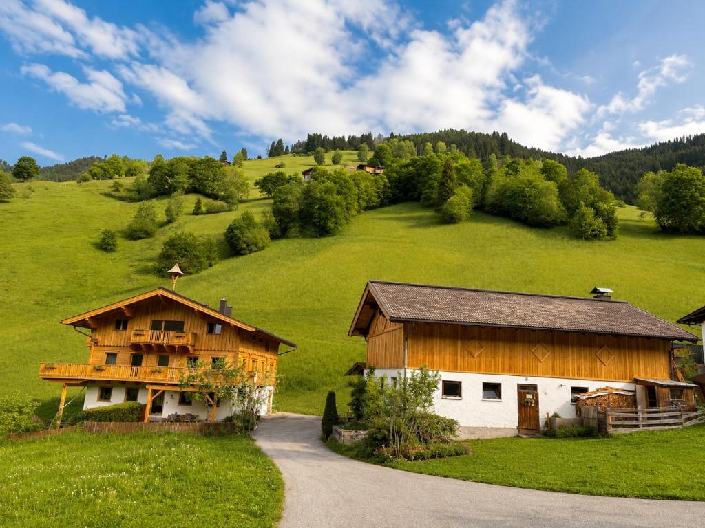 a barn on a green hill with a house at Antenbachhof in Grossarl