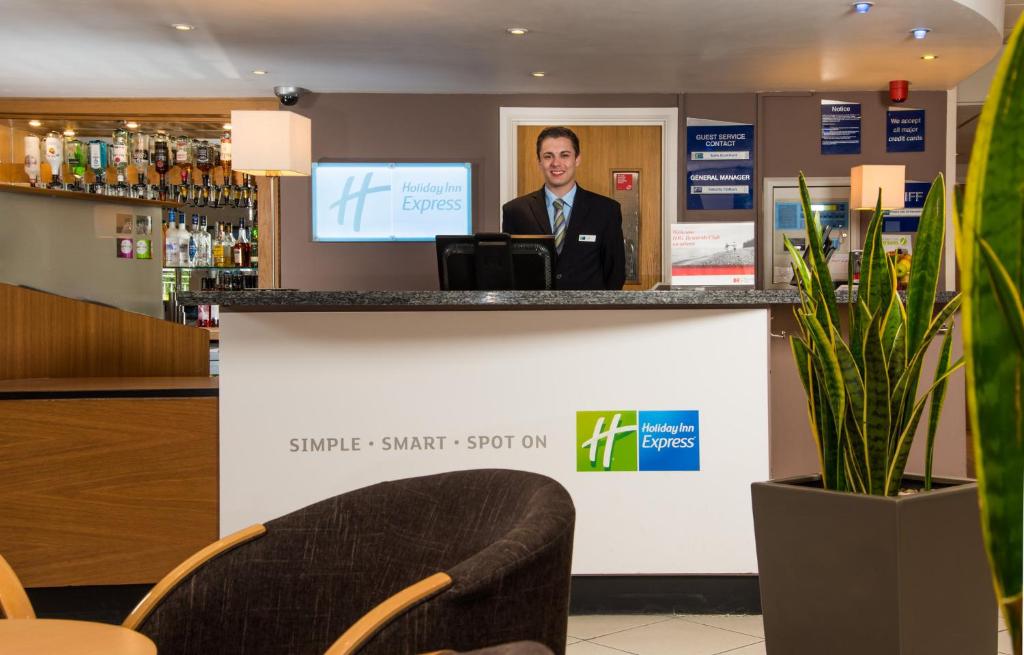 a man standing at a counter in a bar at Holiday Inn Express Gloucester - South by IHG in Gloucester