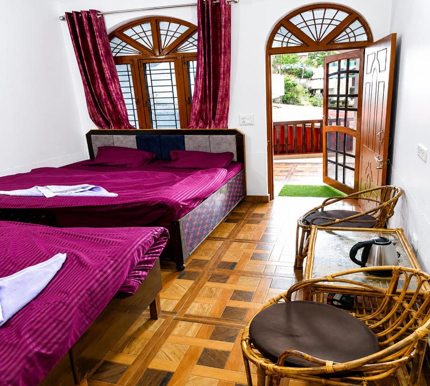 a bedroom with two beds and two chairs in it at Hotel Padam Niwas in Ukhimath