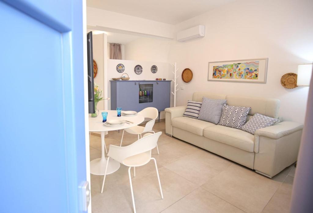 a living room with a couch and a table and chairs at Appartamento Ralf - In Centro in Castelsardo