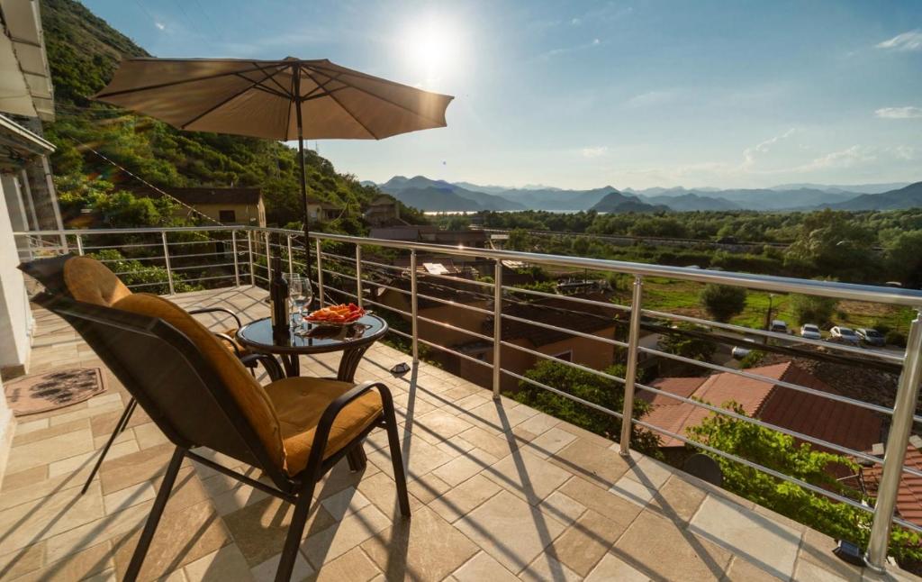 a patio with a table and an umbrella on a balcony at The Best Lake View Studios Borisic in Vranjina