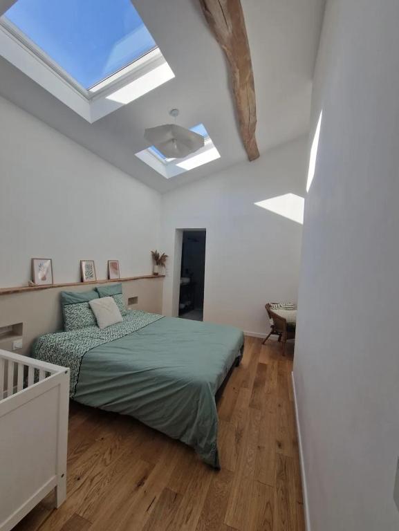 a white bedroom with a bed and a skylight at Suite privée charentaise in Romegoux