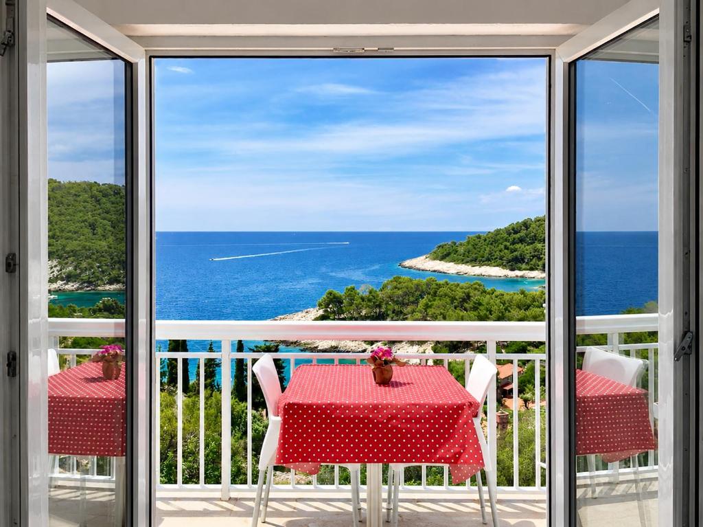 a table and chairs on a balcony with a view of the ocean at Apartments Marija Magdalena in Hvar