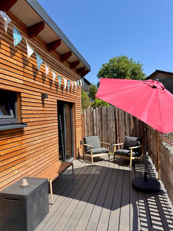 a patio with a red umbrella and chairs on a deck at Luxus Kutsche in Grafengehaig
