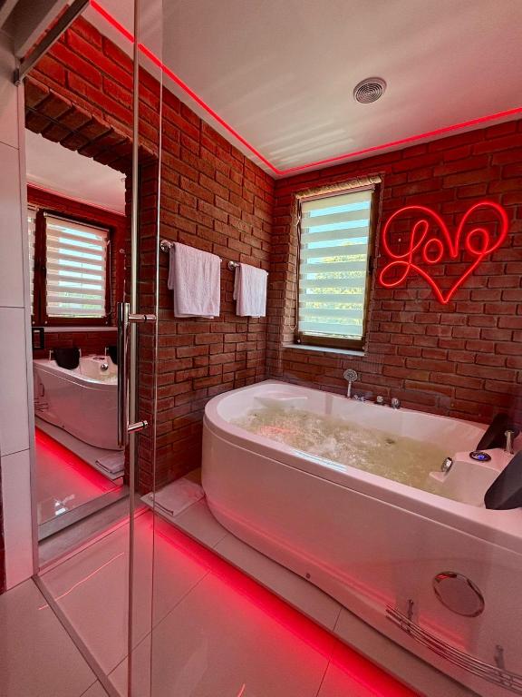a bathroom with a tub with red lights in it at Apartament "Loft Love" Jacuzzi SPA z dużą wanną z hydromasażem dla Dwojga in Gniezno