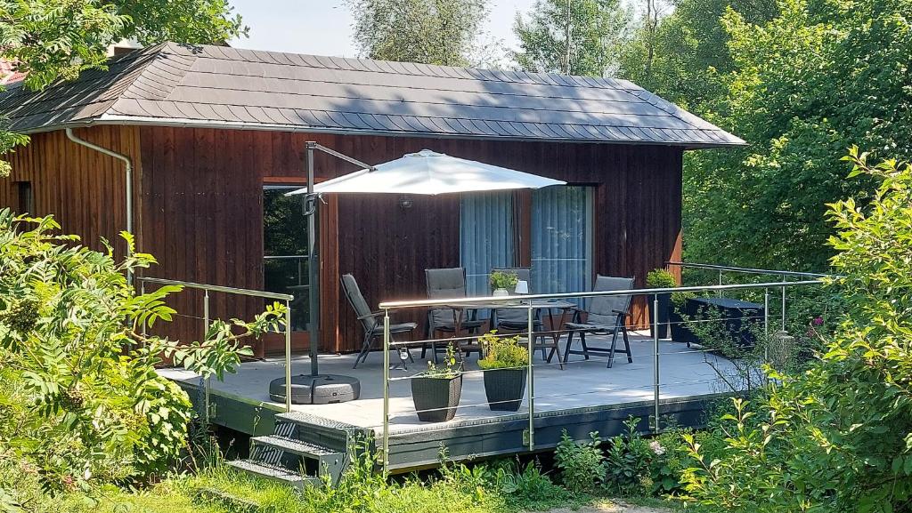 a house with a deck with a table and an umbrella at Ferienhaus Triebesgrund in Zeulenroda