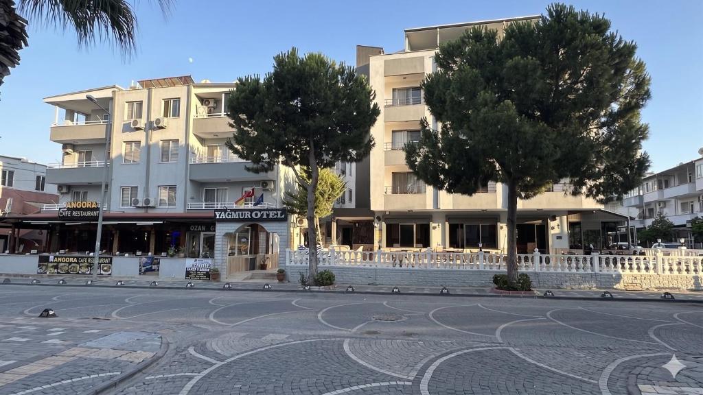 a building with trees in front of a street at Yağmur Apart Otel in Didim