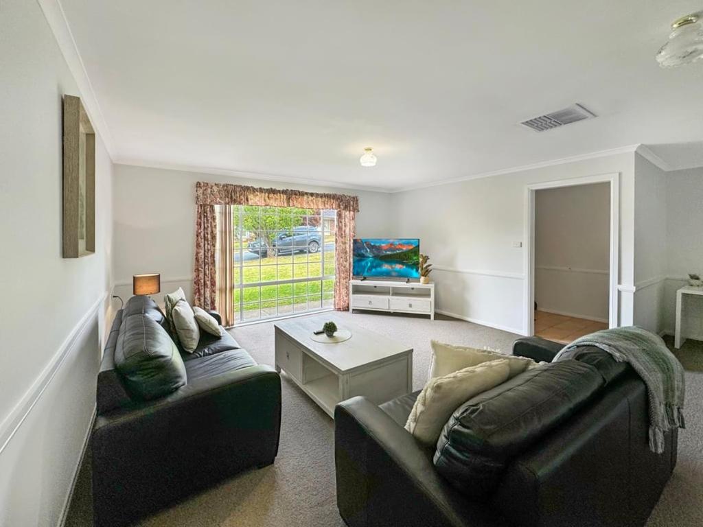 a living room with two couches and a table at Suburban Bliss - Elegant Villa 2 in Wagga Wagga