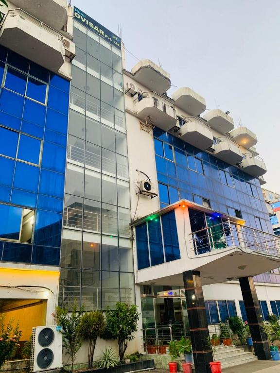 a large building with blue glass windows and trees at Hotel Ovisar in Cox's Bazar