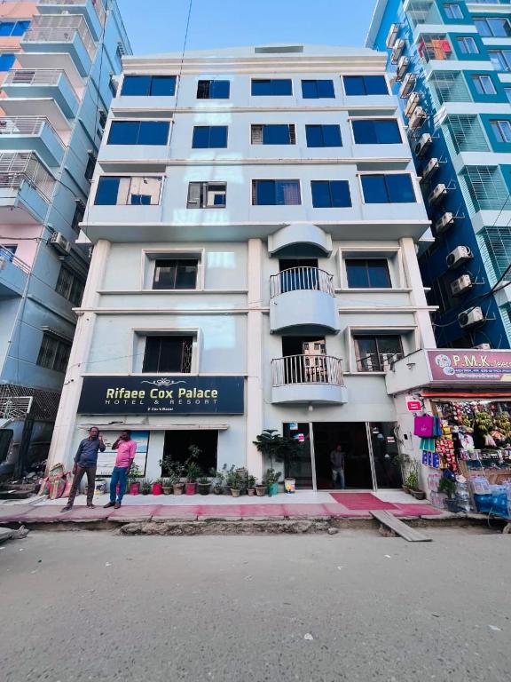 a white building with people standing in front of it at Rifaee Cox Palace in Cox's Bazar