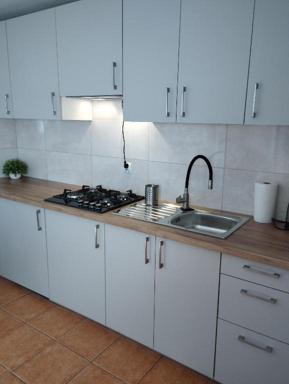 a kitchen with white cabinets and a sink at Domki pod brzózkami in Bodzentyn