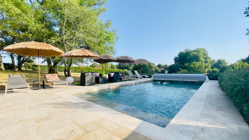 a swimming pool with chairs and umbrellas at Chez Les Garçons Mobile home vintage, confortable avec piscine in Sarlat-la-Canéda