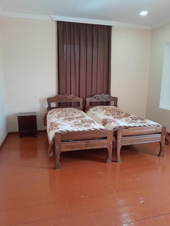 two twin beds in a room with wooden floors at Guest house Tea in Kvareli
