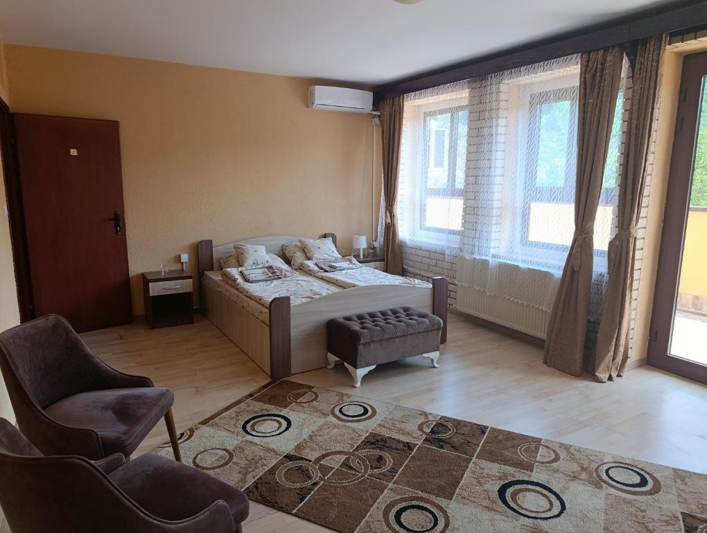 a bedroom with a bed and a chair and windows at Jasen restoran in Jarmenovci