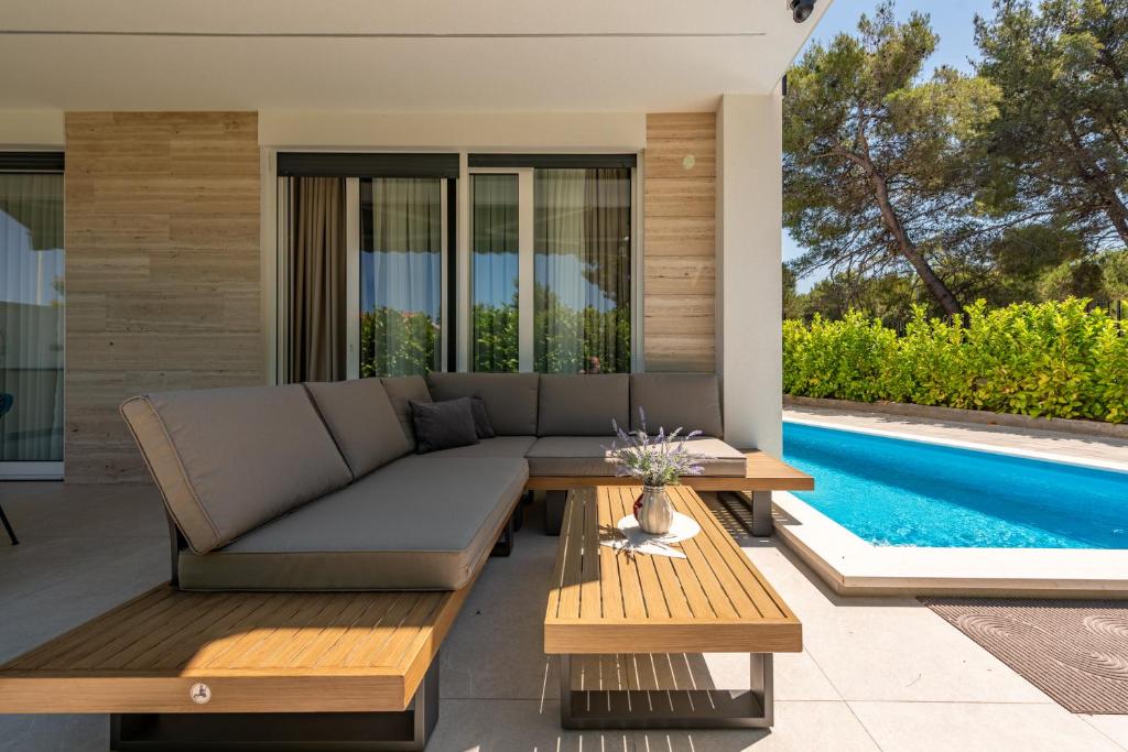 a patio with a couch and tables next to a swimming pool at Villa Nika with pool & parking near Zadar in Bibinje
