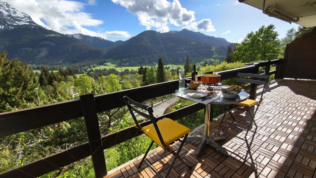 a table and chairs on a balcony with mountains at El Balcón des Diablerets in Les Diablerets