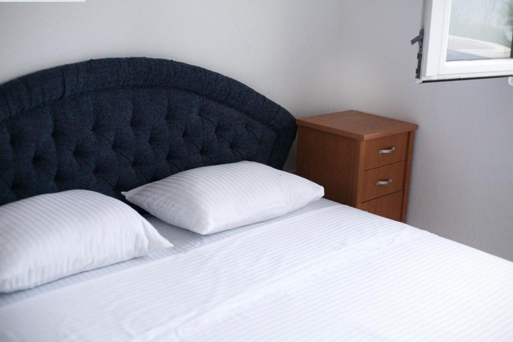 a bed with a black headboard and a white pillow at Apartman Vujović Orahovac in Trstenik