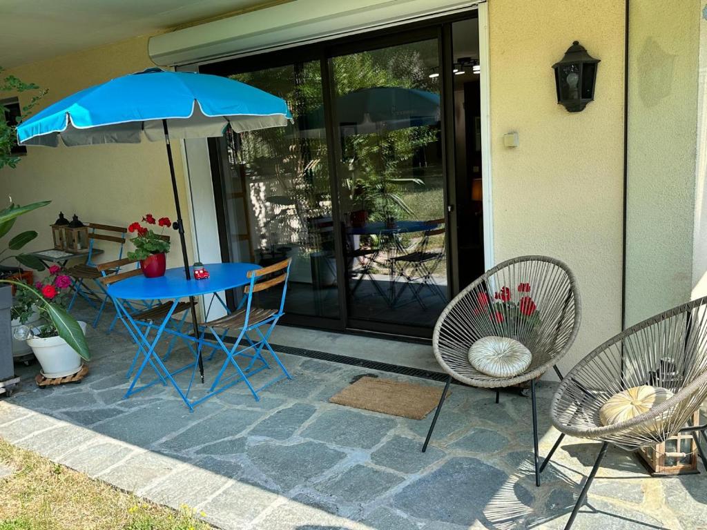 a blue table with chairs and an umbrella on a patio at Appartement 55 m2 proche de la plage in Sévrier