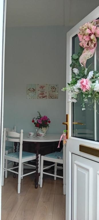 a dining room with a table and chairs and flowers at Rose Cottage in Kilrean