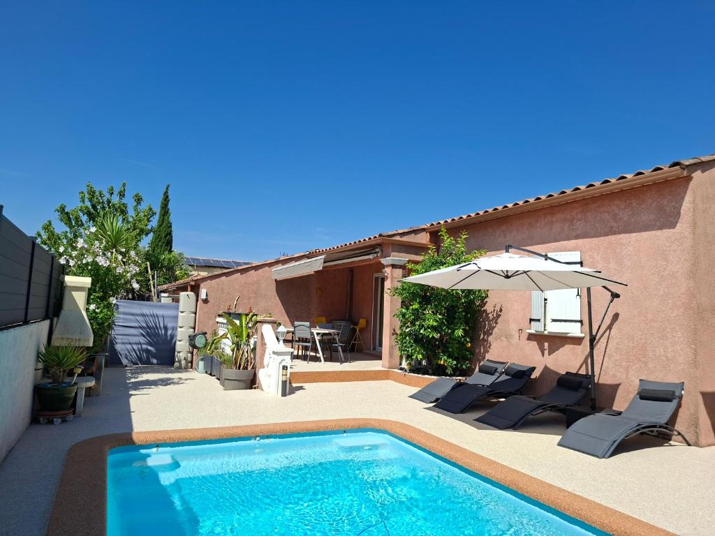 a pool with chairs and an umbrella next to a house at La Milhaud in Milhaud