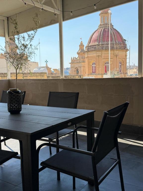 a table and chairs with a building in the background at Cardinal Rooftop Townhouse by Aureum in Birgu