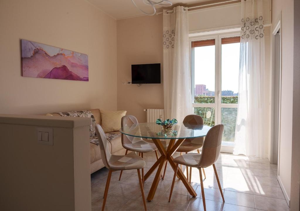 a dining room with a glass table and chairs at Casa Thaila - Box auto gratuito in Milan