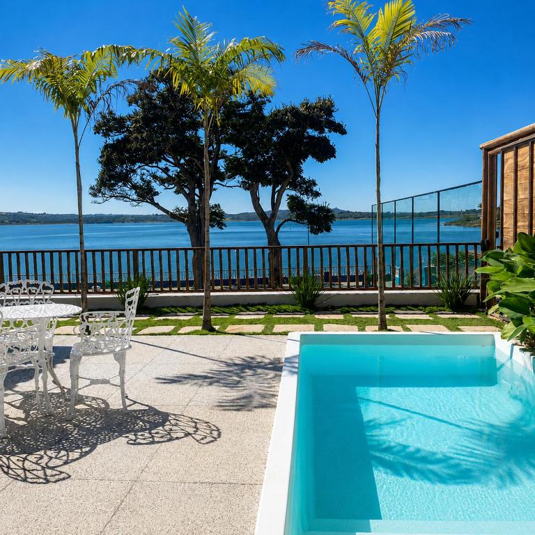 a pool with a table and chairs and a view of the water at Pousada Recanto das Águas - Fama MG in Fama