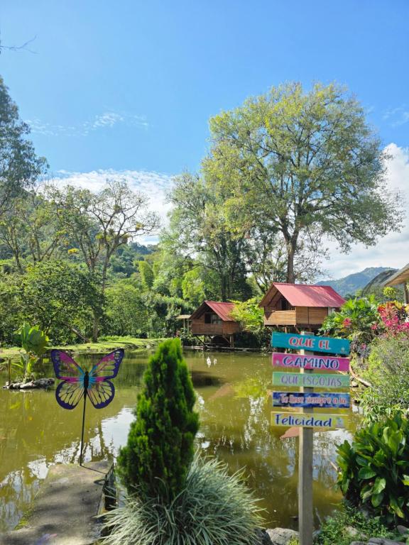a garden with a butterfly sign and a pond at El portal de Bariloche in Ibagué