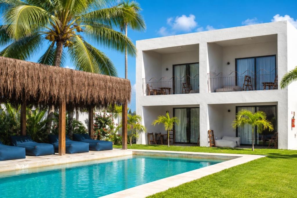 a villa with a swimming pool and palm trees at Luau Hotel in Flecheiras