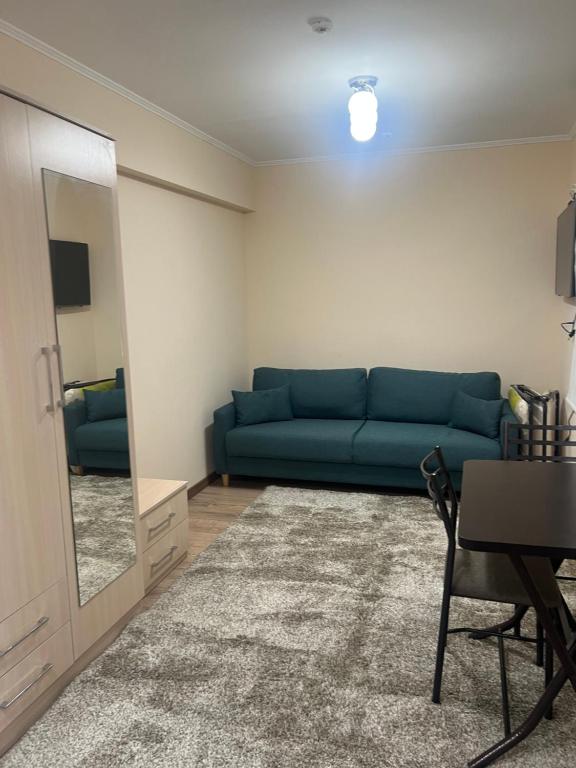 a living room with a blue couch and a mirror at Radugawest2 in Koshkolʼ