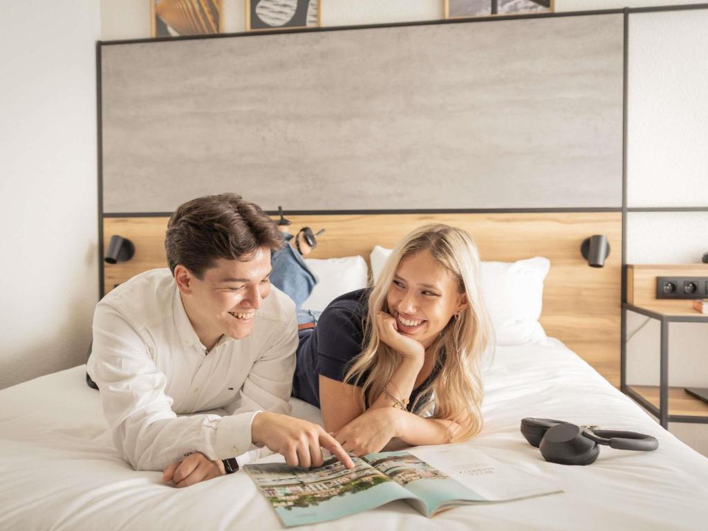 a man and woman laying on a bed reading a magazine at ibis Antwerpen Centrum in Antwerp
