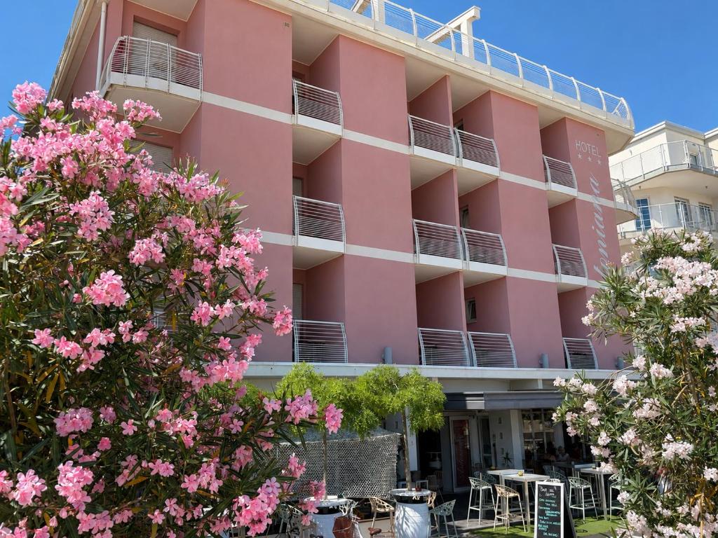 ein rosa Gebäude mit rosa Blumen davor in der Unterkunft Hotel Antoniana in Caorle
