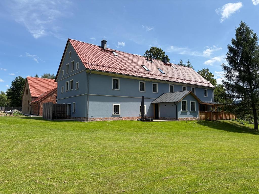 a large gray house with a large grass yard at Agroturystyka Muraszkowa Zagroda in Giebułtów